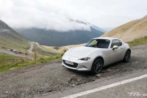 Un Mazda MX5 blanco en una carretera de montaña. Las opiniones sobre este coche son muy positivas, ideal para disfrutar de paisajes así.