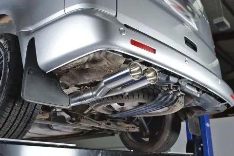 Detalle del sistema de escape de un vehículo plateado. Consulta el precio de limpieza del filtro de partículas.
